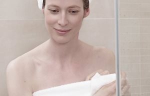 alt="Woman after shower, wrapped in a towel, towel turban on her head."