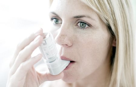 Woman using inhaler.