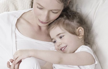 Mother and child lying close to each other, cuddling.