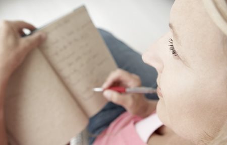 Woman writing something down in note pad.