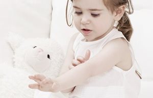 Little girl playing with stuffed animal.