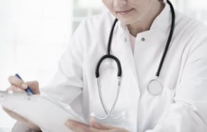 Doctor with stethoscope around neck, writing something down.